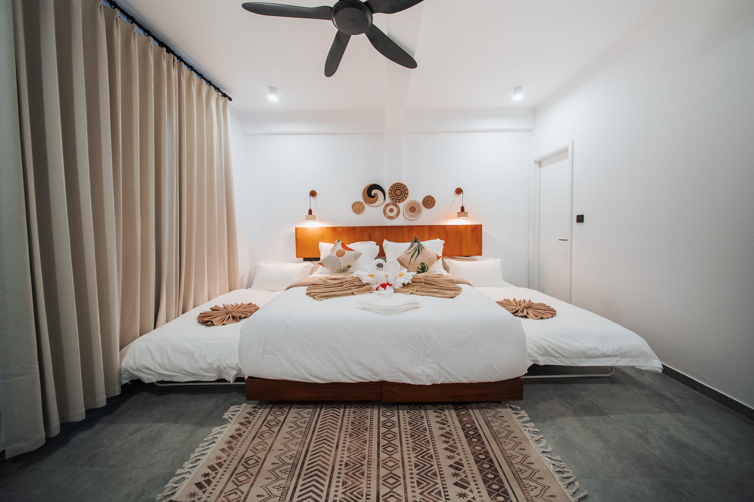 A king room beneath its ceiling fan, a woven rug underfoot